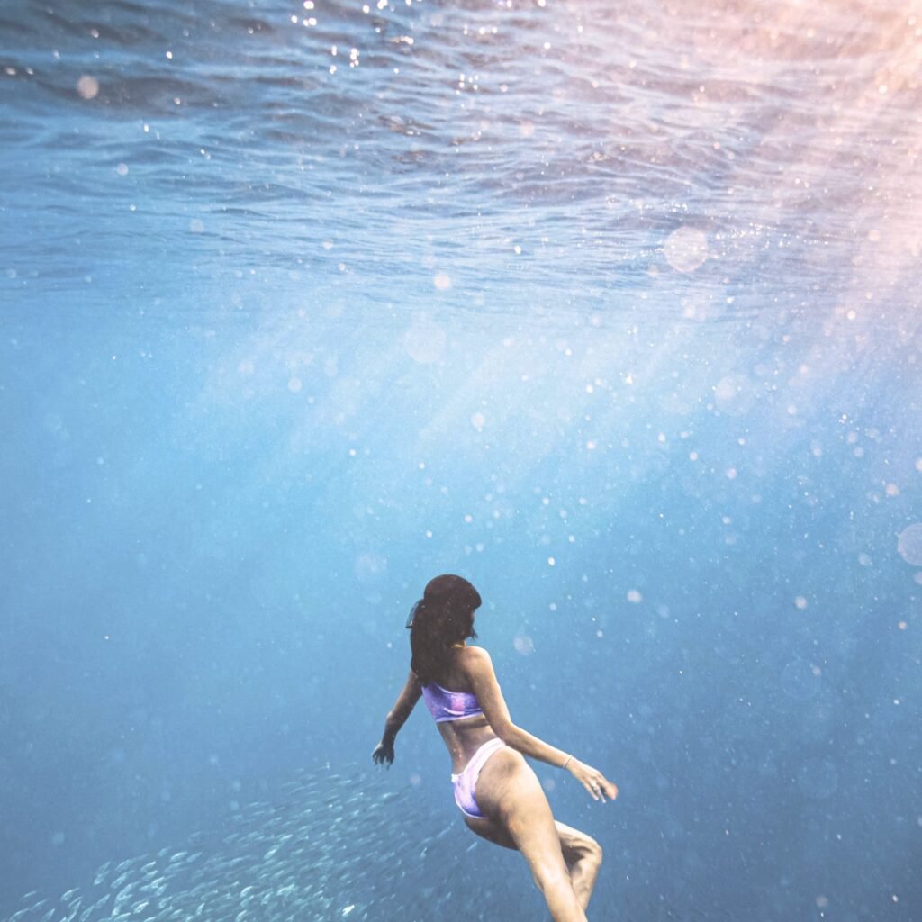 Woman underwater with light shining from above representing midlife transits